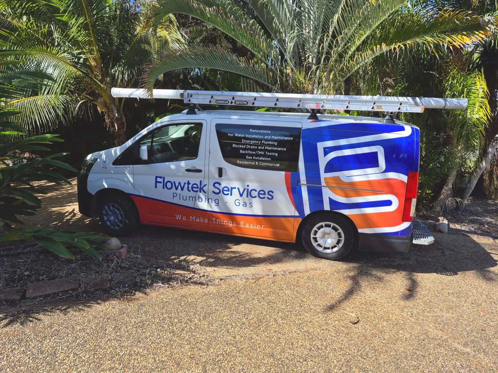 The Flowtek Services van photographed from the side, showing the wordmark, the list of services on the window and the ladder on the roof rack